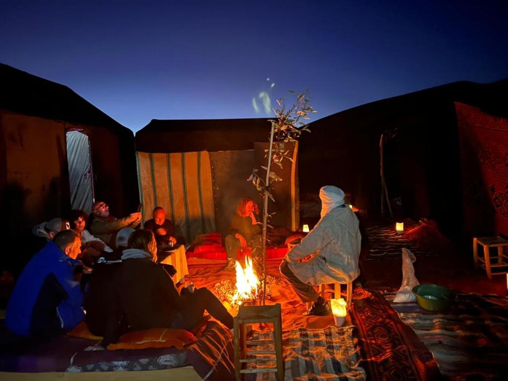 AdrouineGambe Camp的一群人坐在帐篷里,围着火堆