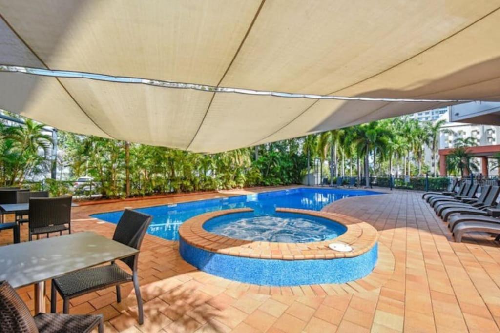 达尔文Resort Style City View King Bed Pool Balcony的庭院内一个带椅子和遮阳伞的游泳池