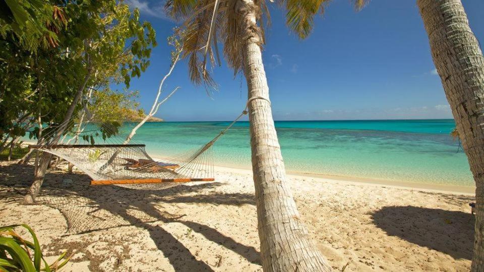 纳库拉岛S@fe Landing Lodge的两棵棕榈树之间的海滩上的吊床