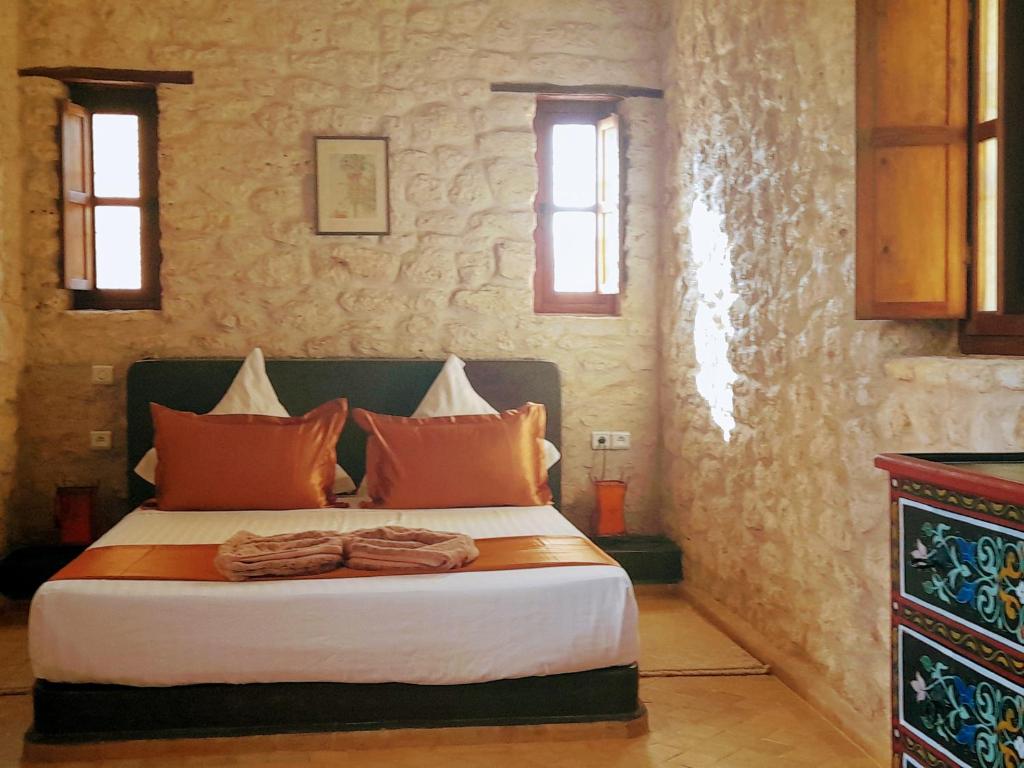 索维拉Riad Mamy Wababi的一间卧室配有一张带橙色枕头的大床