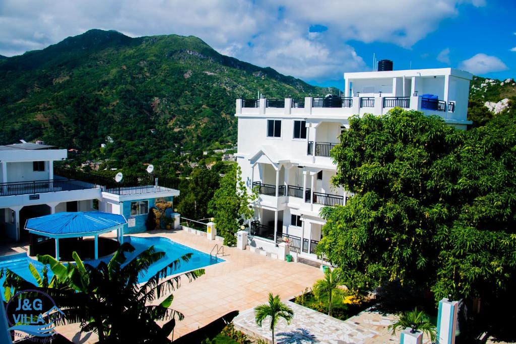 海地角J&G Villa Hotel的一座带游泳池和山脉的建筑