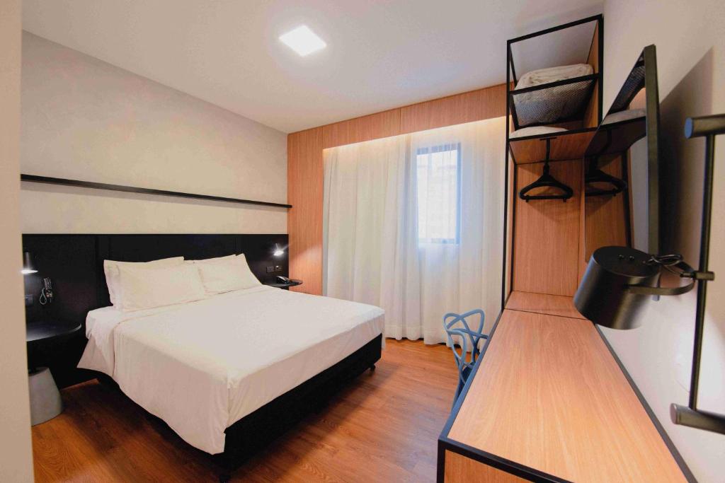 库里提巴库里提巴购物宜必思酒店的一间卧室设有一张床和一个书架