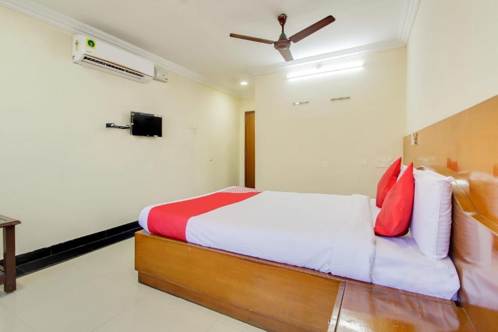 蒂鲁帕蒂OYO Srinivasa Residency的一间卧室配有红色和白色枕头的床
