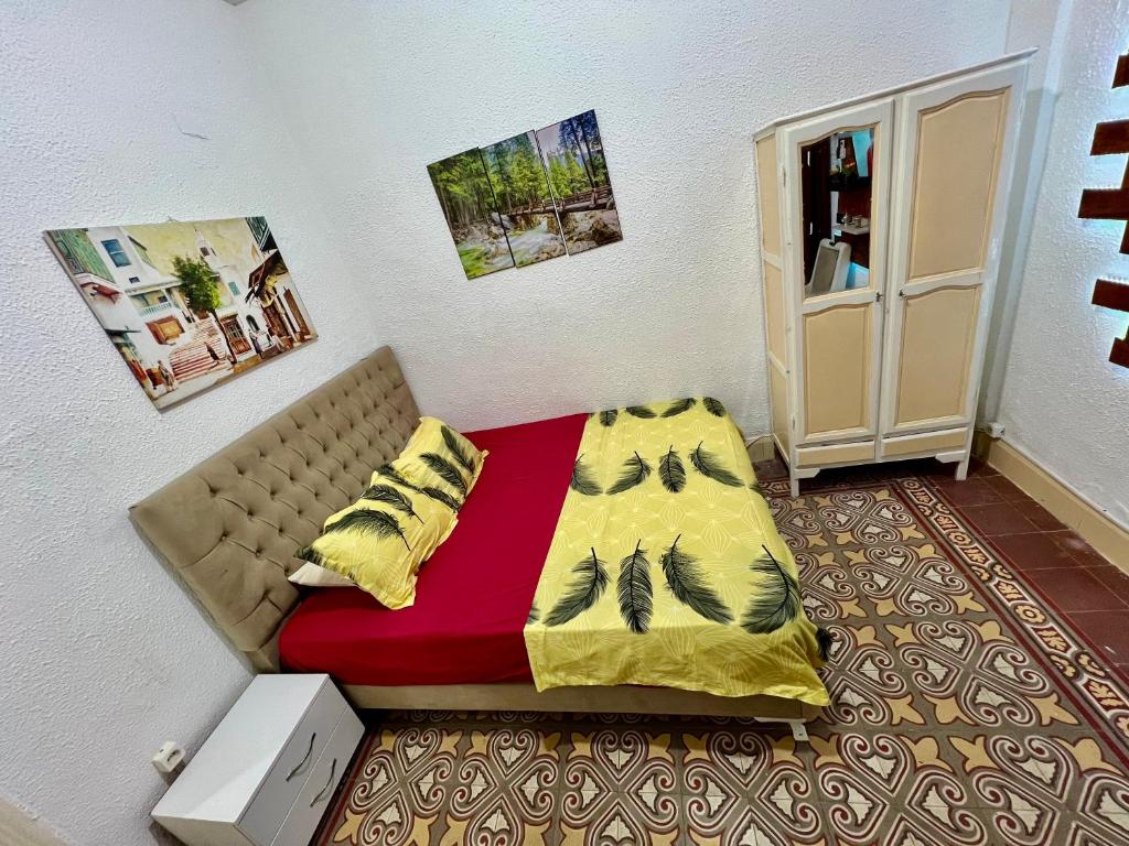 突尼斯Un studio au centre ville de Tunis的小卧室配有一张带红色和黄色毯子的床