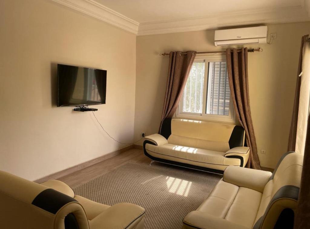 FatickSuperbe 2pieces avec climatisation的客厅配有椅子和平面电视