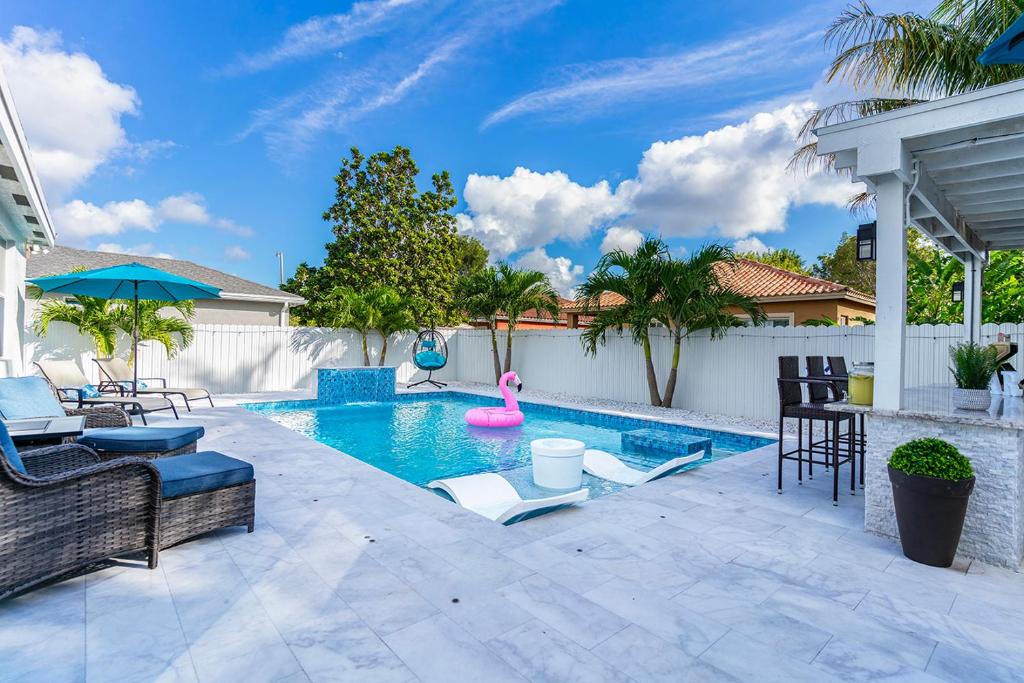 迈阿密Lux Backyard/Heated Pool/Everglades/Speedway/Keys!的后院带椅子和粉红色火烈鸟的游泳池