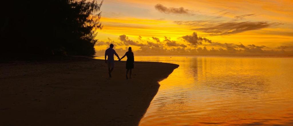 AmuriResort Tava'e的两人在日落时分在海滩上散步