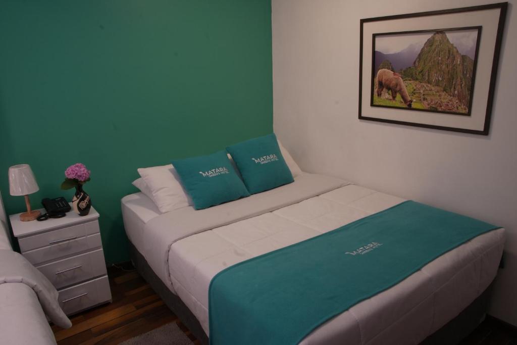库斯科MATARA GREENS HOTEL的一间小卧室,配有一张蓝色墙壁的床