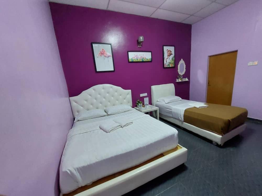 瓜拉大汉塔曼内加拉河景山林小屋的一间卧室设有两张床和紫色墙壁
