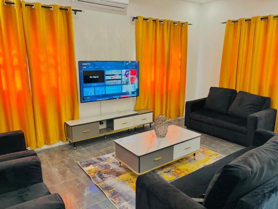 KpaliméLES 9 Plurielles T3 KPALIME KOUMA KONDA的客厅配有橙色窗帘和电视