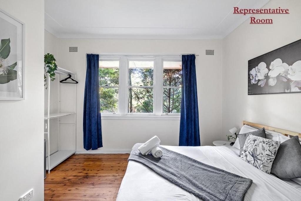 KillaraSerene Killara Guesthouse的一间卧室配有一张带蓝色窗帘的床和一扇窗户