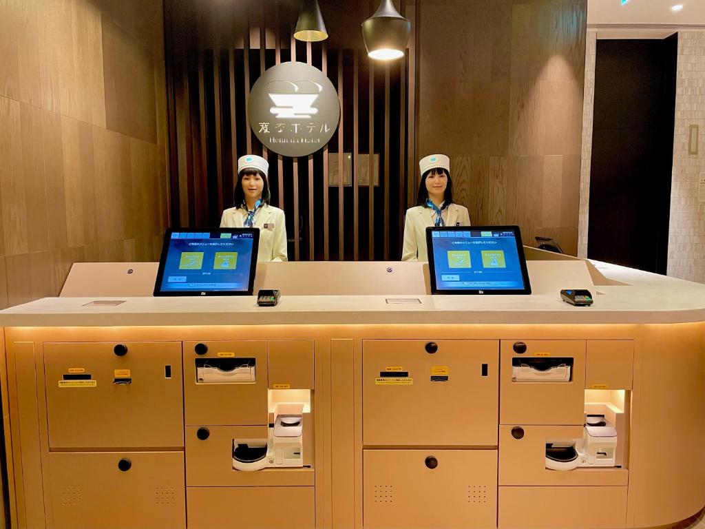 东京Henn na Hotel Tokyo Ginza的两名厨师用手提电脑站在柜台后面
