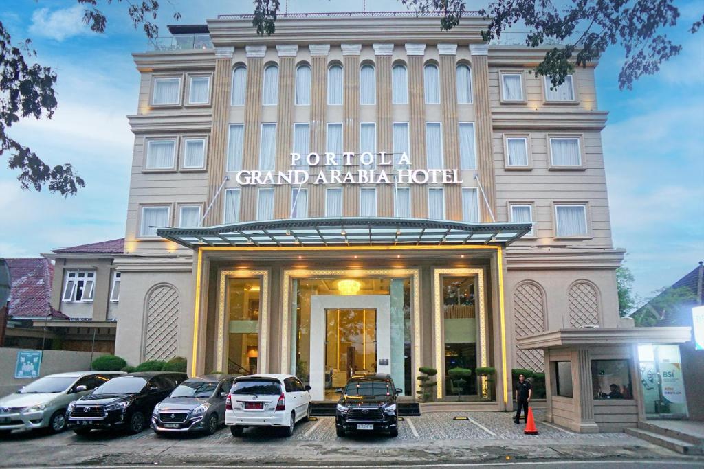 班达亚齐Portola Grand Arabia Hotel的门前有车辆停放的酒店