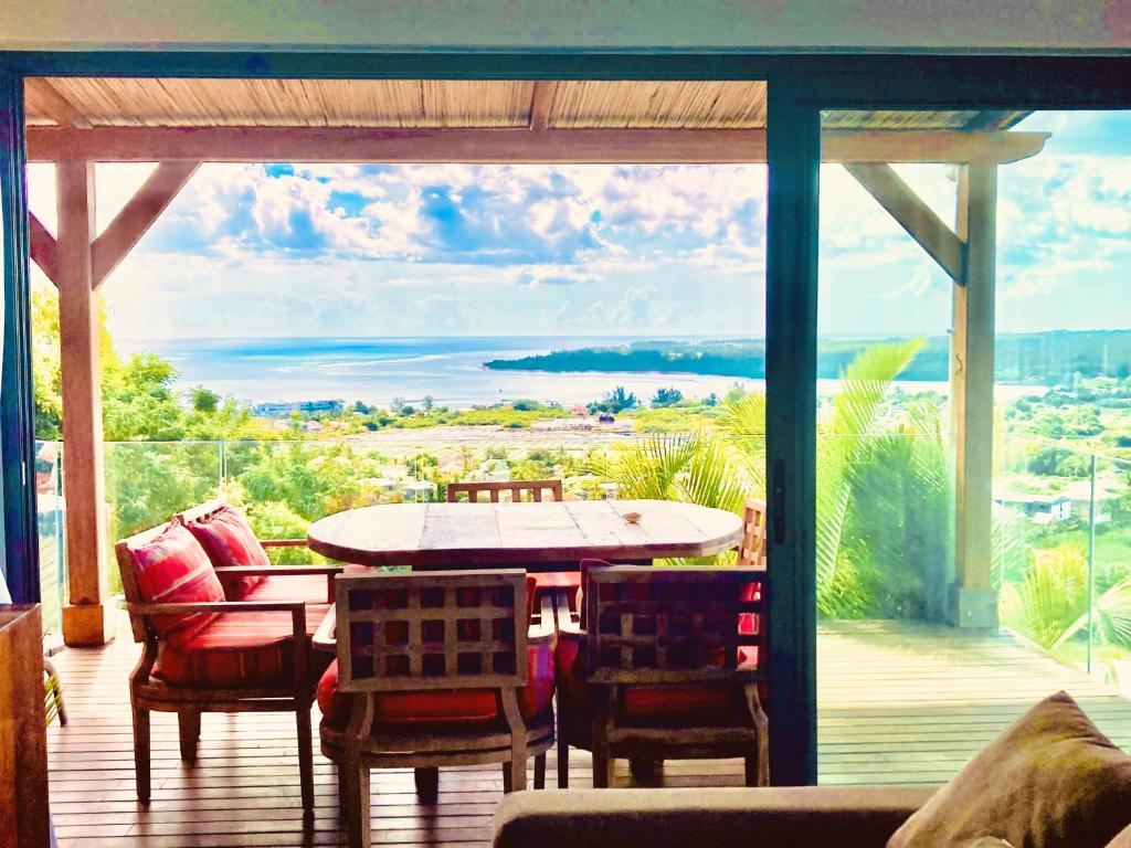 塔马兰Villa Teranga avec vue panoramique sur la baie de Tamarin的一个带桌椅的庭院和一个大窗户。