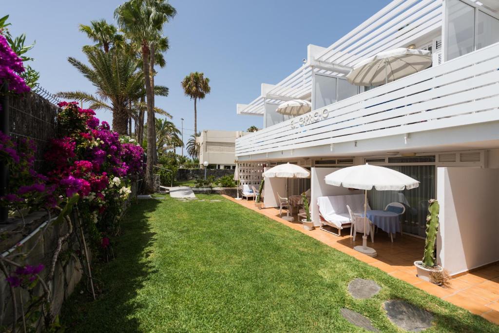 马斯帕洛马斯埃尔卡普里科公寓酒店的一座带草坪和遮阳伞的房屋的后院