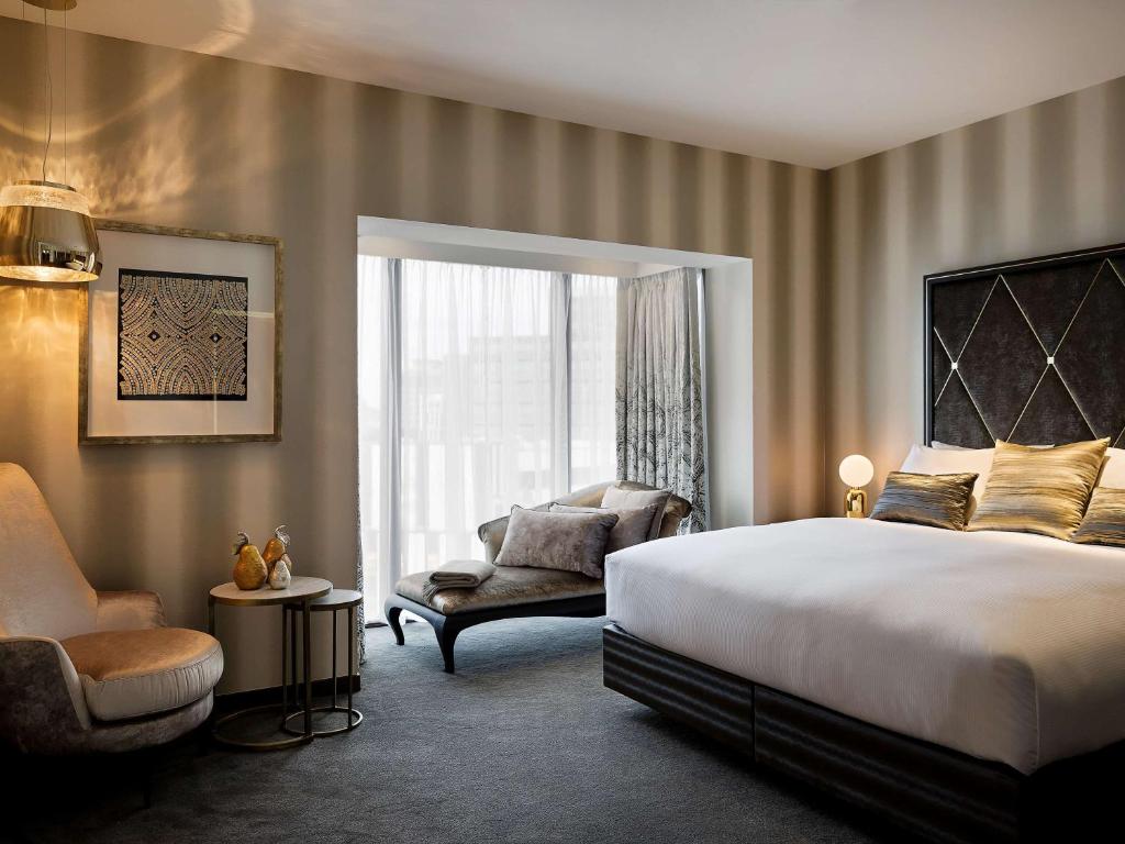 惠灵顿惠灵顿索菲特酒店的卧室配有床、椅子和窗户。