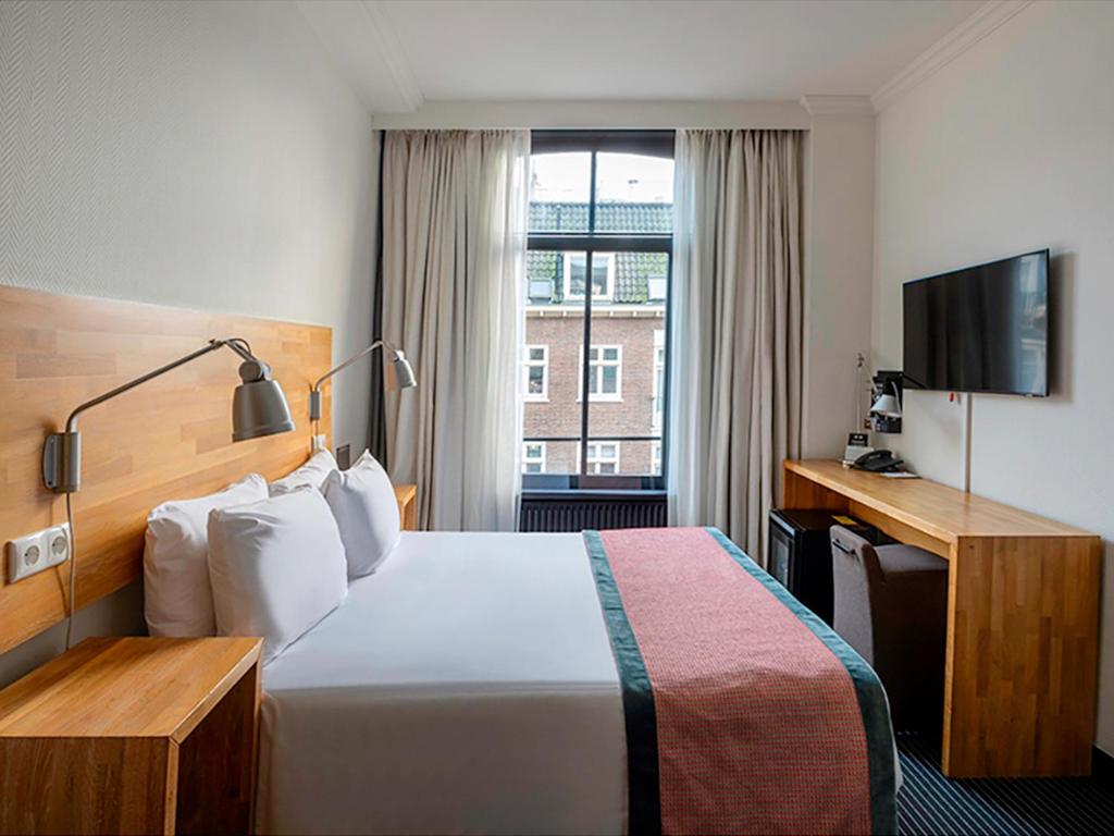 阿姆斯特丹Catalonia Vondel Amsterdam的酒店客房,配有床和电视