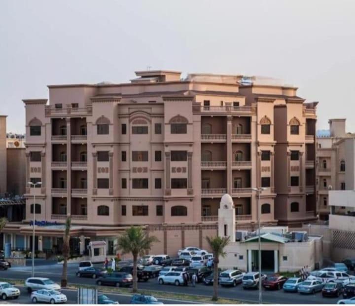 阿可贺巴فندق كارم الخبر - Karim Hotel Khobar的停车场内停放汽车的大型建筑