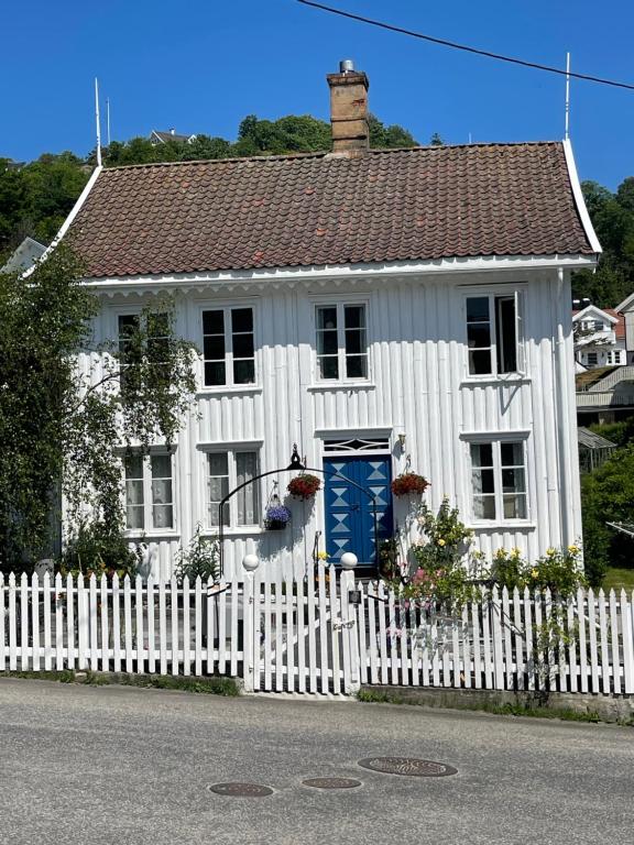 曼达尔Sommerdrøm i sør的白色的房子,有白色的栅栏和蓝色的门