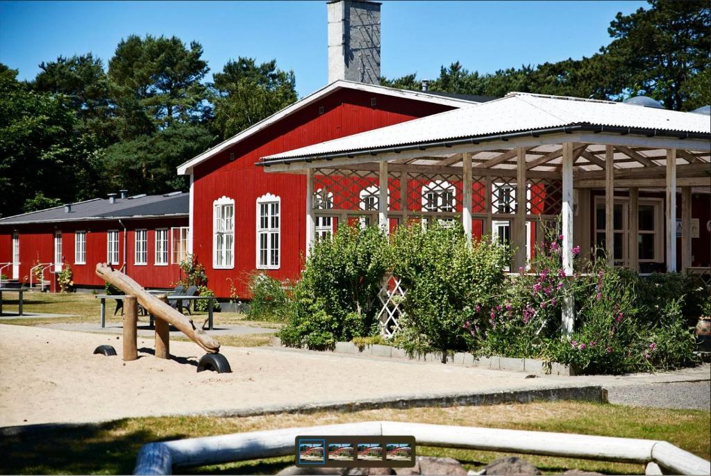 伦讷Rønne Vandrerhjem的一座红色的建筑,前面有一个游乐场