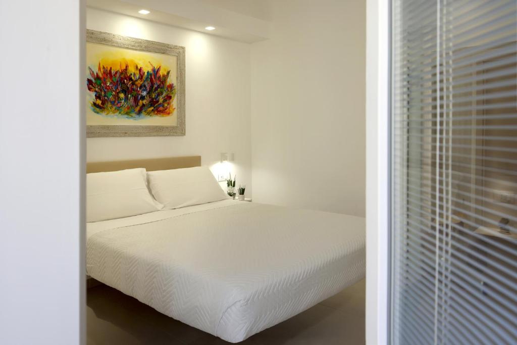 泰尔莫利Ruffini Rooms的卧室配有白色的床和墙上的绘画作品