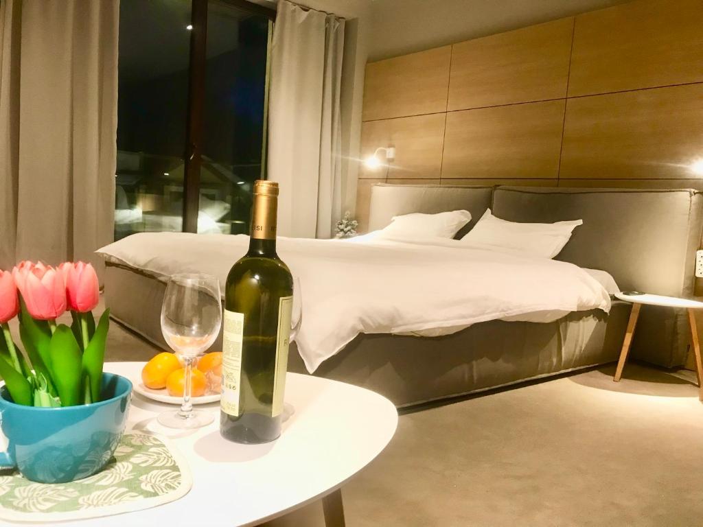 古多里New Gudauri Panorama View Loft II的卧室配有一瓶葡萄酒和一张鲜花桌