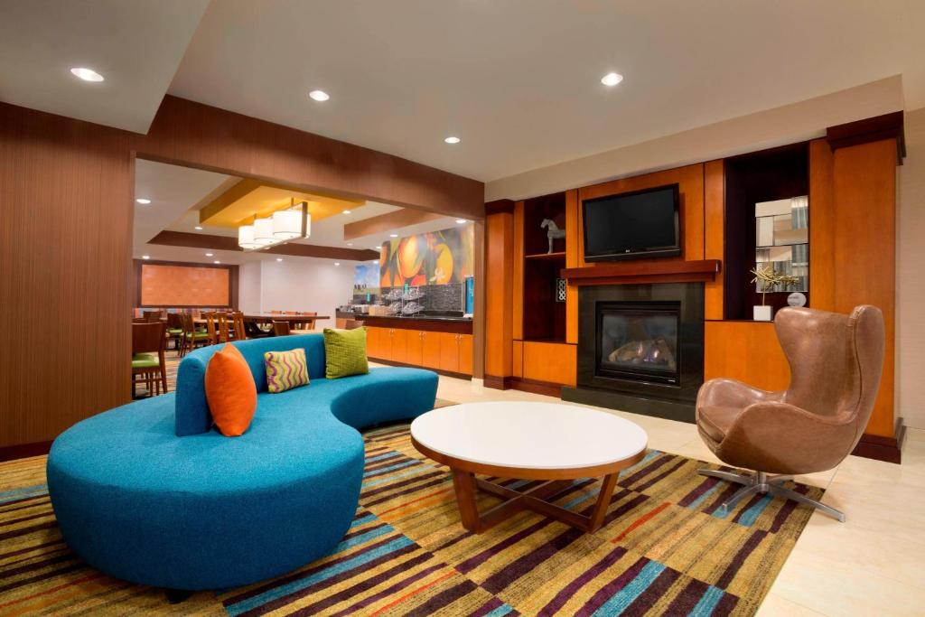 沃思堡沃斯堡大学路费尔菲尔德套房酒店的客厅设有蓝色的沙发和壁炉