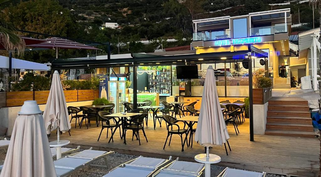 伏罗拉Hotel Tramonto Vlore的一间带桌椅和遮阳伞的餐厅