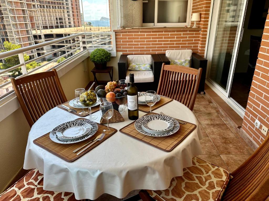 卡拉德费斯特拉特Benimar 1的阳台上的一张桌子,上面放有盘子和一瓶葡萄酒