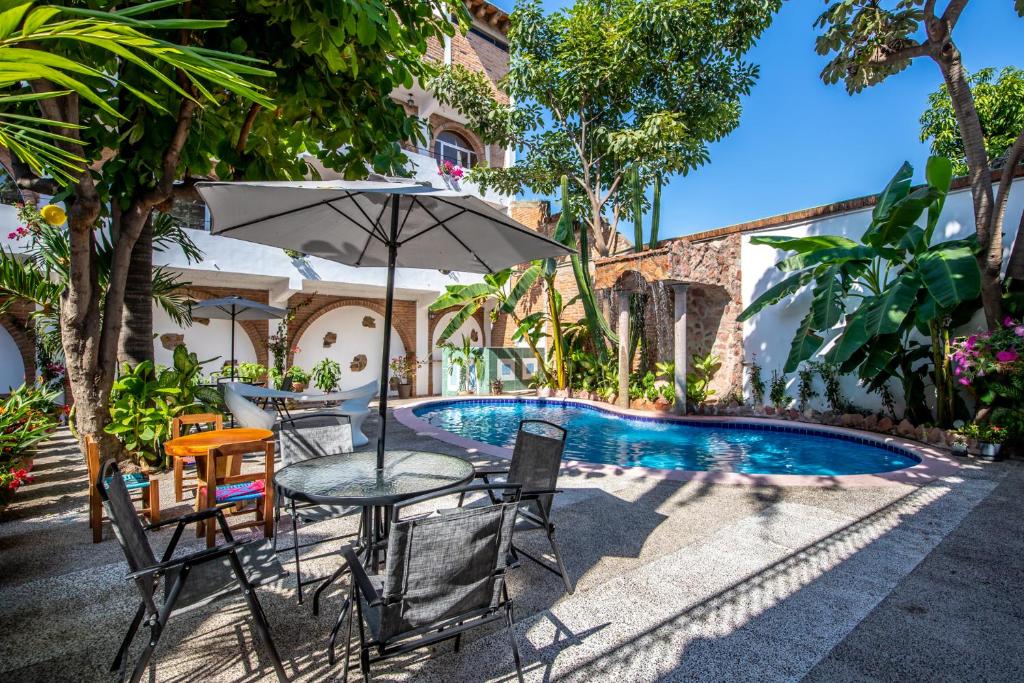 巴亚尔塔港Hacienda Lord Twigg - Hotel & Suites的游泳池旁带遮阳伞的桌子