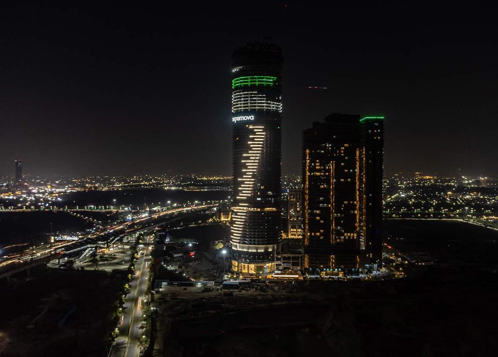 诺伊达The Opulence Suite 41st Floor City View的一座高大的建筑,晚上有绿灯