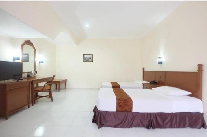 梭罗梭罗萨希德库苏马萨希德酒店的酒店客房配有一张床、一张书桌和一台电视。