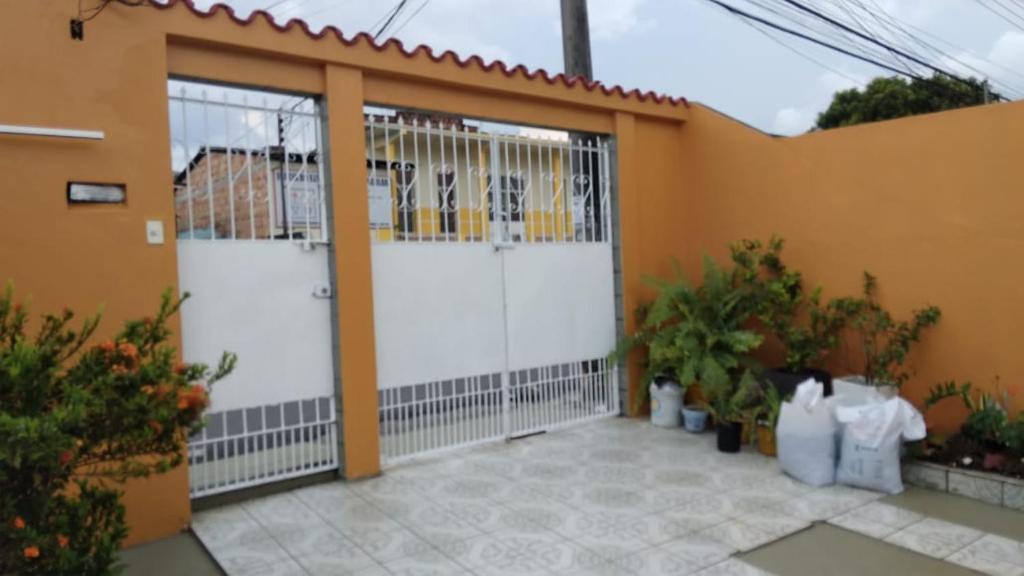 马瑙斯Casa Edgar的车库,有两个白色门,一些植物