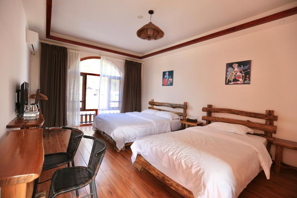 阳朔阳朔小龙河酒店的一间卧室配有两张床和一张桌子及椅子