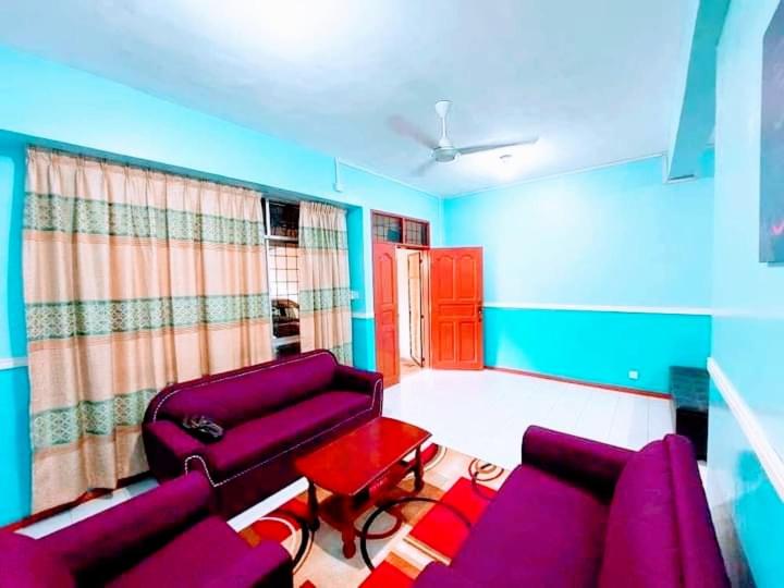 山打根ILHAM HOMESTAY Taman Sejati Mile 7的客厅配有紫色沙发和红色桌子