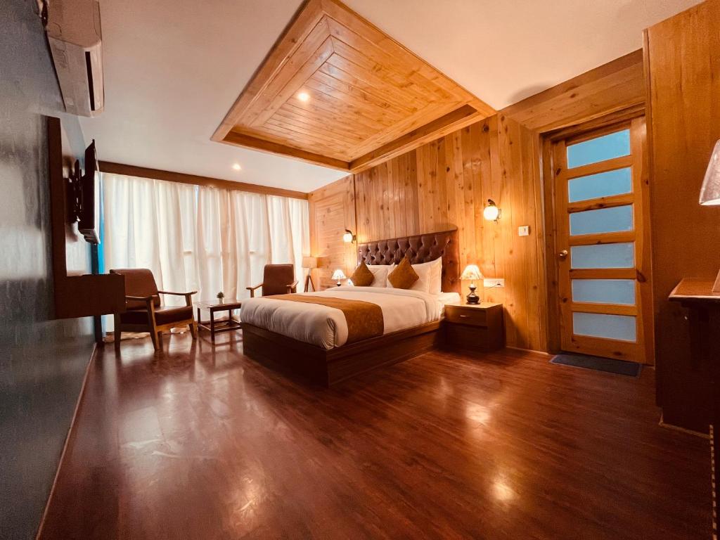 马拉里TATA Vista Resort Mall Road Manali - Centrally Heated & Air Cooled的酒店客房带一张床、一张桌子和椅子