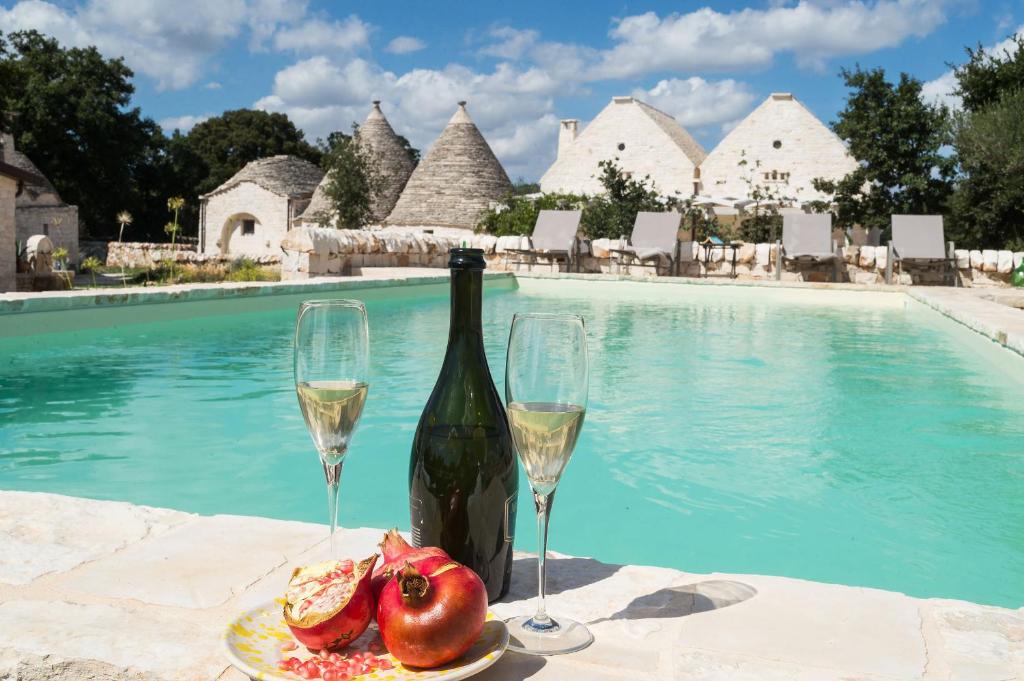 阿尔贝罗贝洛十门度假屋的游泳池旁的一瓶葡萄酒和两杯酒