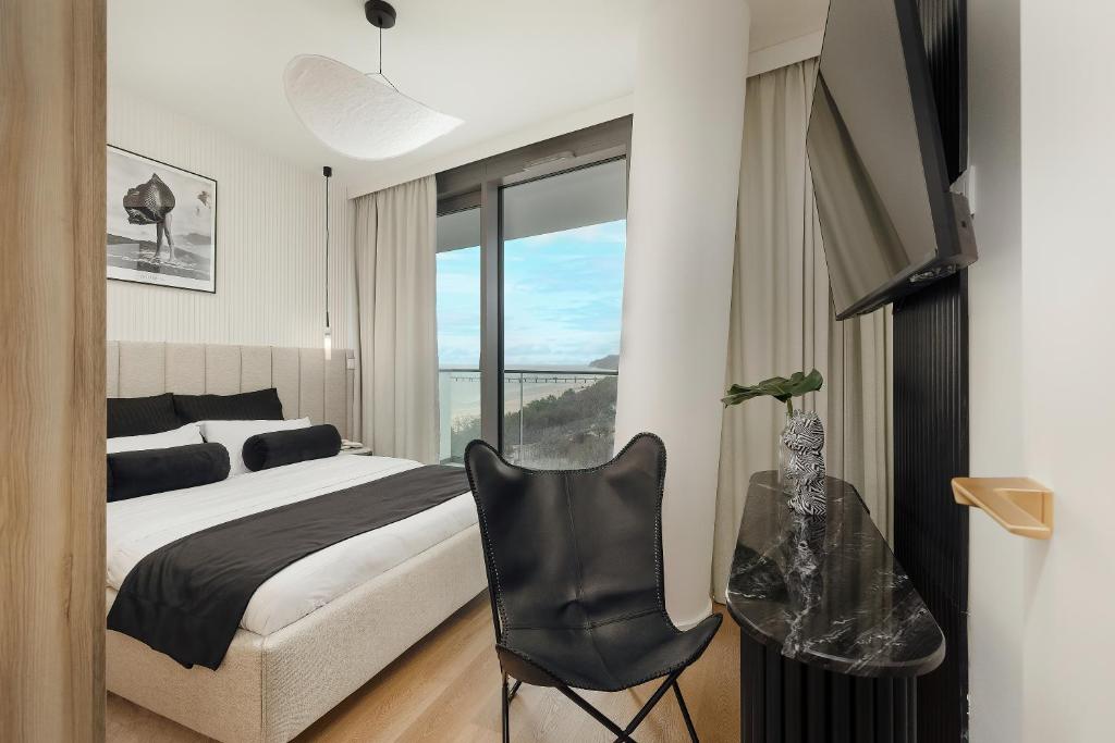 米兹多洛杰WAVE 10th Floor Baltic View的卧室配有床、椅子和窗户。