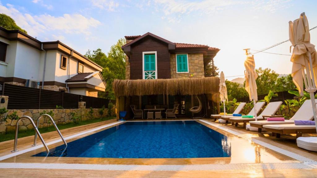 穆拉Marmaris Çamlı Mahallesinde Lüx Dizayn Edilmiş Luxury Villa的一个带椅子的游泳池以及一座房子