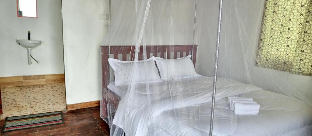 卡巴莱Ruhija Gorilla Guest House的卧室配有带白色床单和枕头的秋千床。