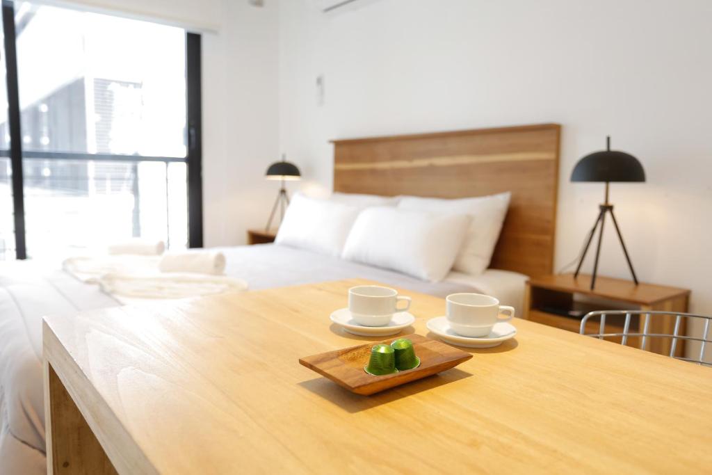 布宜诺斯艾利斯OWN Belgrano Studios & Suites的一间卧室配有床和一张带杯子和盘子的木桌
