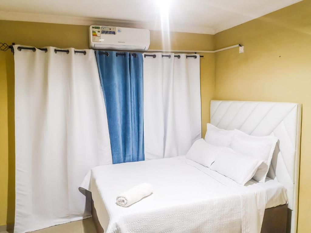 利文斯顿Wanita Apartments的卧室配有白色床和蓝色窗帘