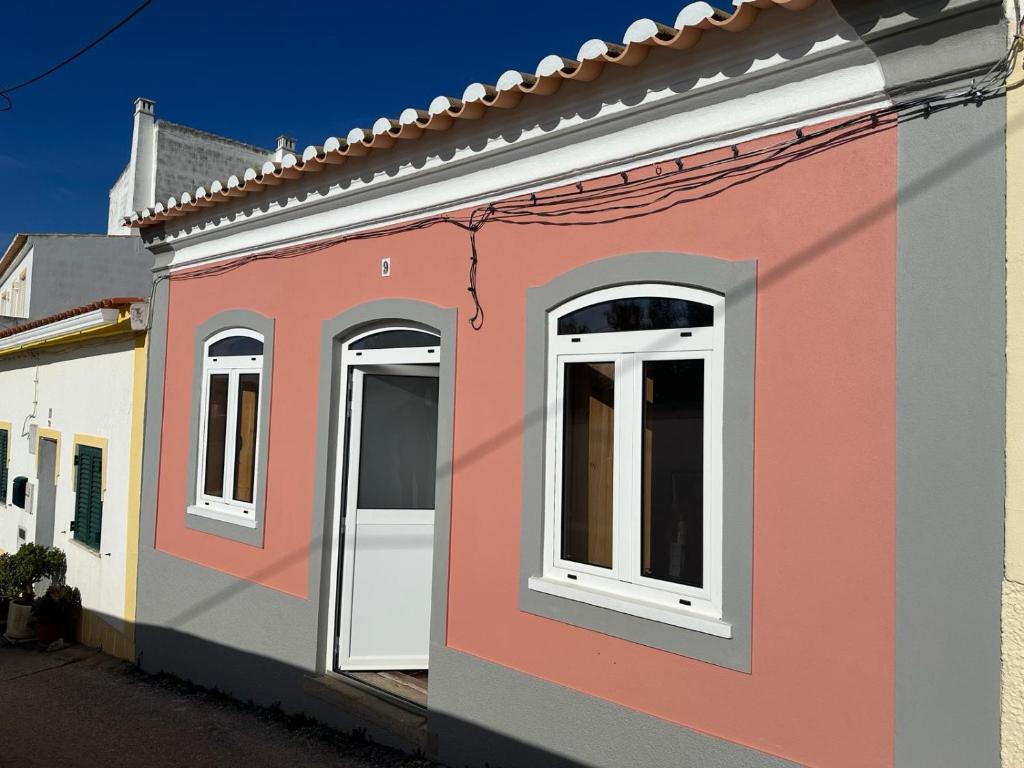 拉波塞拉WavePortugal Surf & Stay的粉红色的建筑,街上有白色的窗户