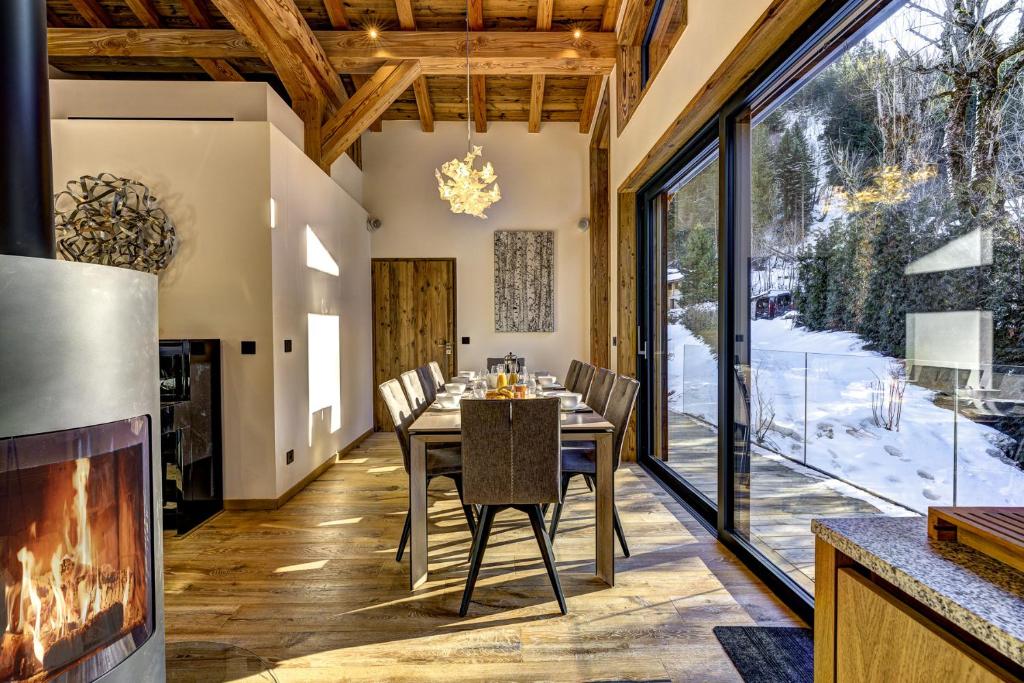 夏蒙尼-勃朗峰Chalet Silver Forest的一间带壁炉和桌椅的用餐室