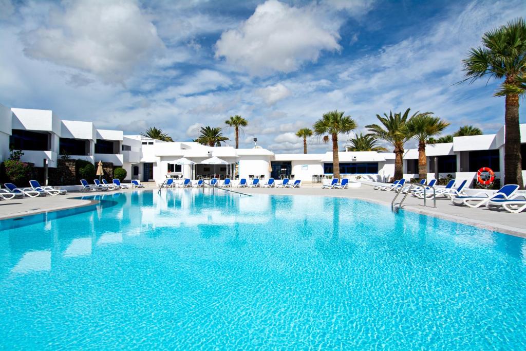 卡门港全景公寓酒店 - 仅限成人入住的一个带椅子和棕榈树的大型游泳池