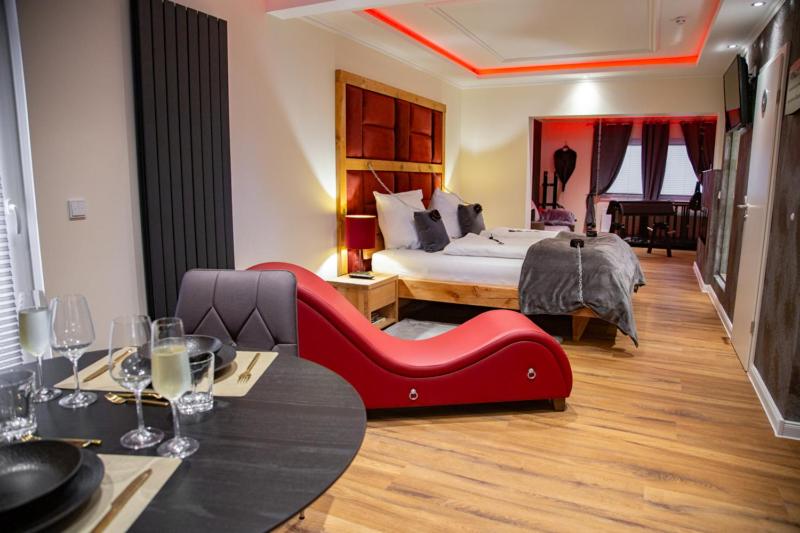 吉夫霍恩exkl. romantisches SM Apartment Black Rose的酒店客房设有一张大床和一张红色沙发。