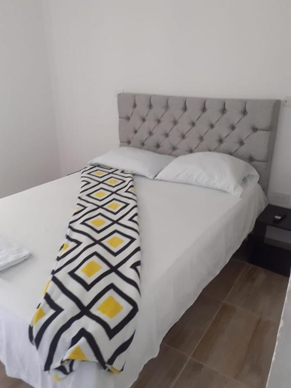 巴耶杜帕尔caribepremiumvalledupar的一张白色的床,上面有黑色和黄色的毯子