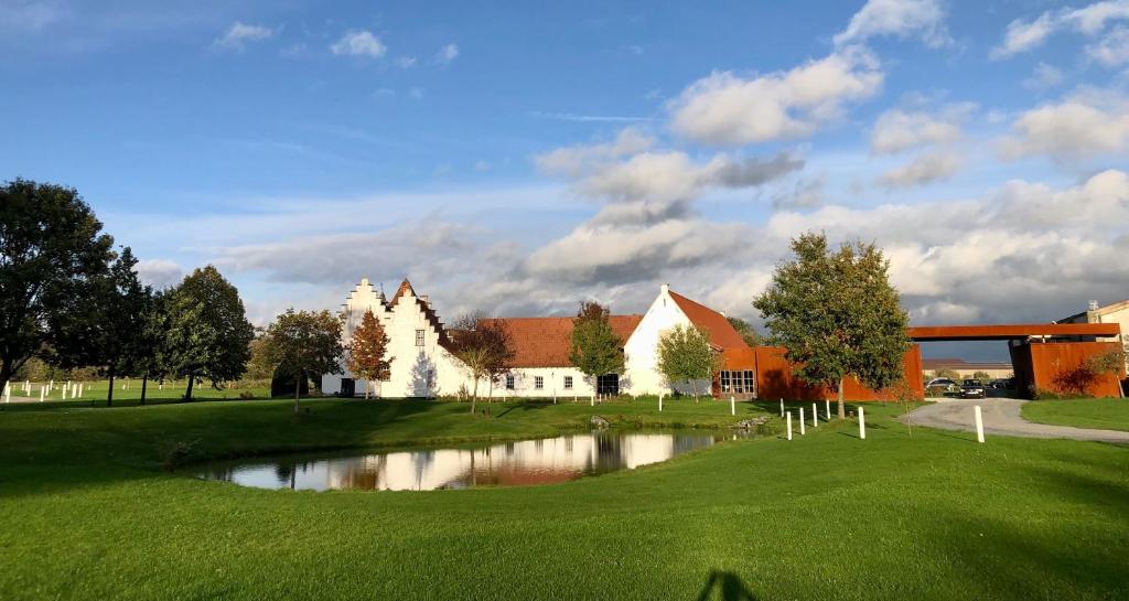 图尔奈Ferme Delgueule的一座高尔夫球场,在一座建筑前设有一个池塘