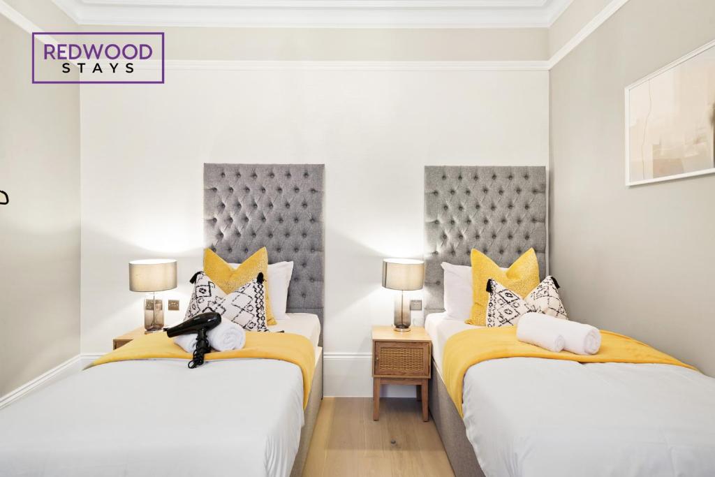 雷丁Premium 1 Bed 1 Bath Apartments For Corporates By REDWOOD STAYS的白色客房内的两张床,配有黄色和灰色枕头