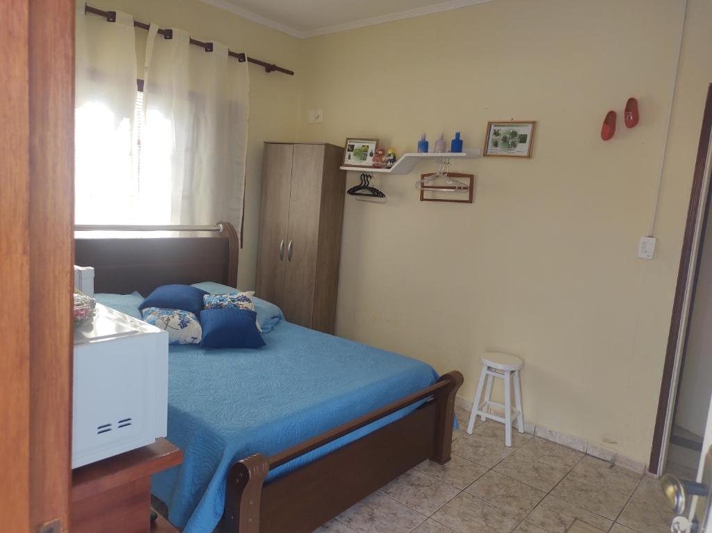 奥兰布拉QUARTO CONFORTAVEL COM GARAGEM的一间卧室配有一张带蓝色床单和凳子的床
